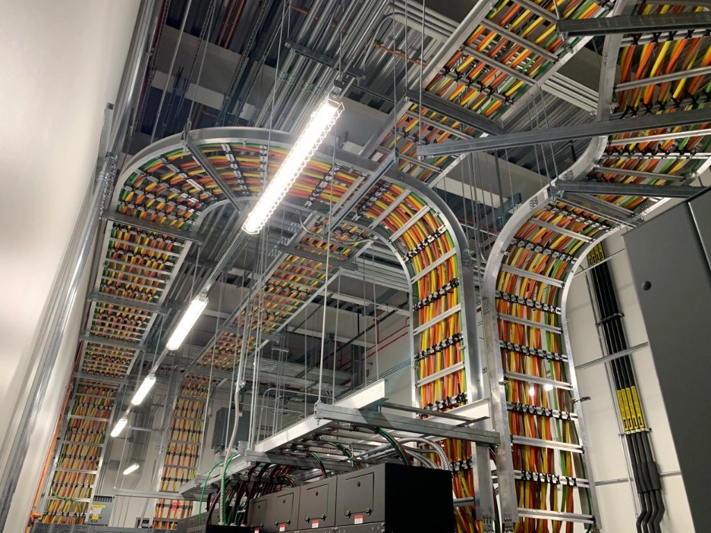 Color-coded data center cabling in overhead trays feeding server cabinets